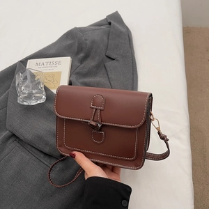 Detail of vintage brown square bag featuring white stitching and toggle clasp closure