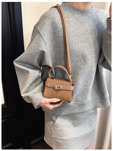 Détail du cuir grainé marron et du fermoir doré tournant sur un sac à bandoulière