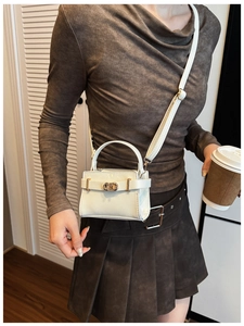 Photo lifestyle d'un mini sac en cuir blanc avec fermoir en métal doré élégant