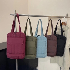 Stylish quilted tote bags for laptops in five colors hanging on a retail display rack