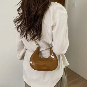French style brown patent leather crescent shoulder bag shown on model for 2025 winter fashion