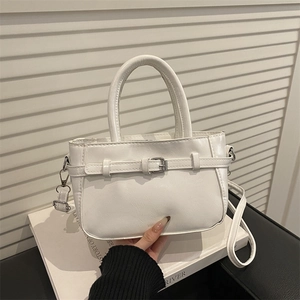 Vintage white top-handle crossbody bag with cracked leather texture shown in a lifestyle shot