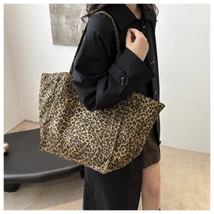 Détail d'un grand sac cabas à motif léopard porté avec un trench-coat noir élégant
