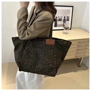 Gros plan détaillé du sac fourre-tout léopard en toile avec poche externe et écusson en cuir