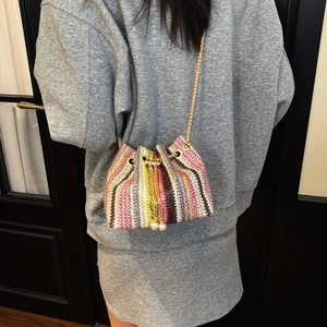 Fashionable woven crossbody bucket bag with colorful stripes and gold chain strap
