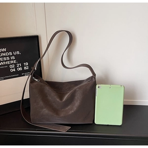 Détail d'un sac hobo en cuir mat marron montrant sa texture lisse et sa grande capacité