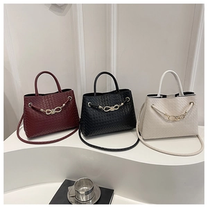 Three woven leather tote bags in burgundy, black, and beige with gold knot chain detail