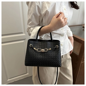 Détail du sac à main tissé noir avec boucle à nœud doré et bandoulière longue assortie