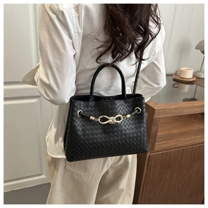 Rear view of a model wearing the black woven leather handbag with gold knot detail