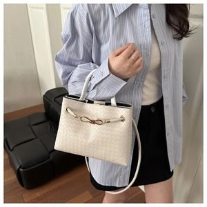 Détail du sac à main tissé blanc crème avec une boucle décorative en nœud doré brillant