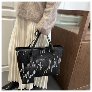 Quilted black tote bag with wave embroidery and mini pouch shown in lifestyle setting