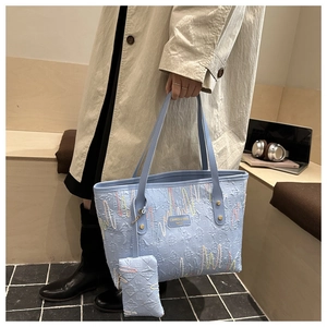 Detail of light blue tote bag featuring 3D embossed texture and colorful wavy embroidery