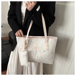 Detail of white tote bag featuring colorful wavy embroidery and pink shoulder strap