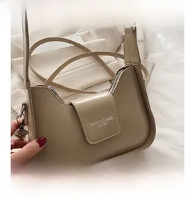 Close-up of apricot baguette bag featuring fashion logo engraving and silver hardware