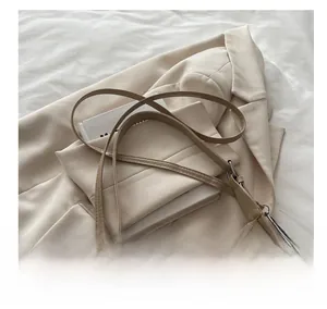 Detail of adjustable faux leather shoulder strap and metallic buckle on beige handbag