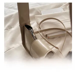 Detailed close-up showing the smooth silver zipper of a beige matte leather shoulder bag