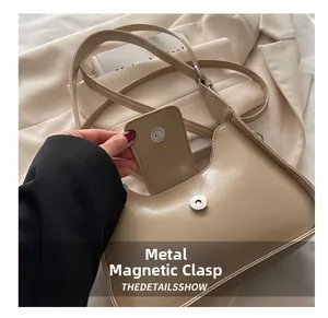 Detail shot of the secure magnetic metal clasp closure on a minimalist beige hobo handbag