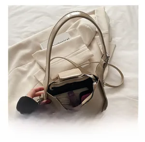 Close-up of beige leather shoulder bag showing spacious interior with cosmetics