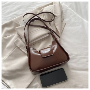 Detail of dark brown leather shoulder bag with magnetic flap and embossed fashion lettering