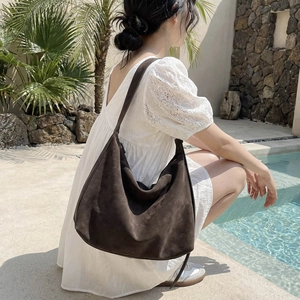 Grand sac hobo rétro en daim marron présenté dans un décor extérieur de vacances