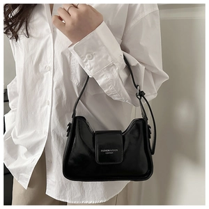 Detailed side view of glossy black leather underarm bag with silver buckle and fashion logo