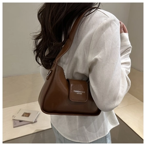 Detailed view of a brown faux leather underarm bag with white logo text and wide strap