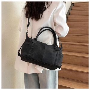 Macro detail of black matte leather tote bag featuring vertical stitching and adjustable strap