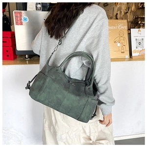 Detail of dark green vintage matte leather tote bag with dual handles and metal hardware