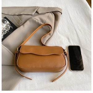 Sac à bandoulière marron en similicuir avec rabat ondulé et smartphone pour échelle