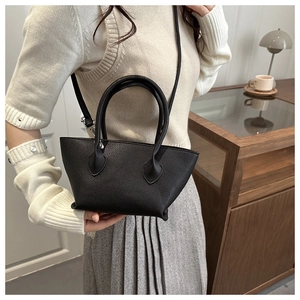 Close-up of black lychee grain leather tote bag featuring dual handles and shoulder strap