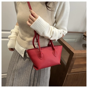 Side view of red trapezoid tote bag in lychee pattern leather worn by model