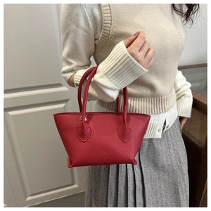 Close-up of red lychee grain leather bucket bag with teardrop metal hardware and handles