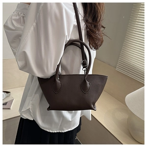 Brown litchi grain leather bucket bag shown in lifestyle setting with silver hardware