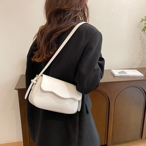 Sac à bandoulière blanc chic avec rabat ondulé porté par un mannequin en studio