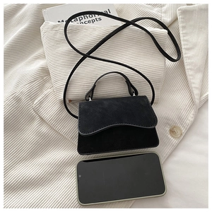 Macro view of mini black matte handbag compared with a smartphone for size scale