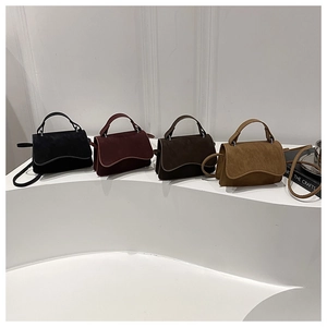 Detailed display of four colorful matte faux suede handbags on a white minimalist pedestal