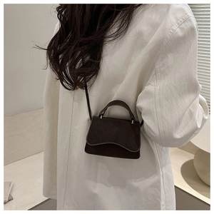Close-up of a mini dark brown frosted leather crossbody bag with top handle and strap
