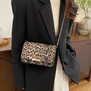 Minimalist leopard print crossbody bag with gold chain strap worn with a black suit