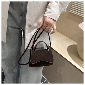 Detail of a dark brown matte leather mini bag with silver hardware and top handle