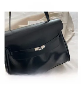 Close-up of black leather texture with silver metal clasp lock on a Kelly style handbag