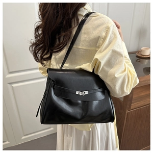 Detailed back view of a black leather shoulder bag with silver buckle on a model