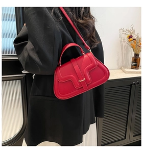 Detail view of red leather crossbody bag with wave-cut flap and gold buckle on a model