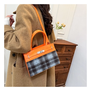 Détail d'un sac bandoulière chic en cuir orange et plaid avec un fermoir rotatif en métal