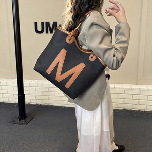 Classic black tote bag with brown leather M letter and shoulder straps for daily commute