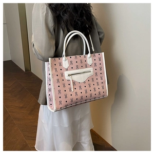 Macro detail of pink tote bag with bear print, white handles, and textured leather finish