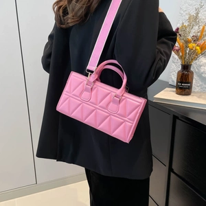 Sac bandoulière rose matelassé à motif triangulaire porté avec un blazer noir