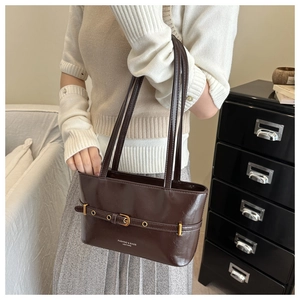 Detail of dark brown leather shoulder bag with gold belt buckle and fashion text