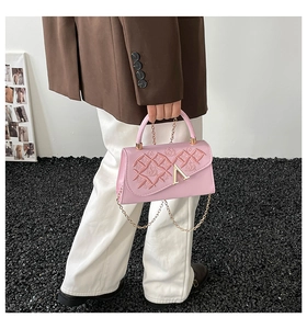 Gros plan du sac à main rose avec motifs de cœurs gaufrés et logo en métal doré