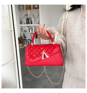 Détail du sac rouge avec broderie ondulée et fermoir métallique doré en forme de A