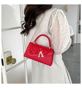 Détail du sac à main rouge en cuir PU avec logo V doré porté par le mannequin